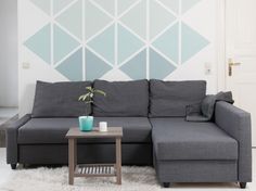 a gray couch sitting on top of a white rug next to a wooden coffee table