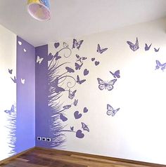 an empty room with butterflies painted on the wall and wood flooring in front of it