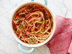 a pot filled with spaghetti and meat on top of a table next to a red towel