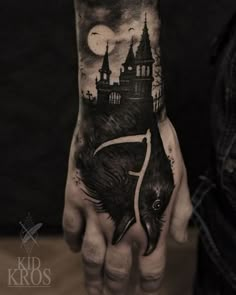 a man's hand with a black and white tattoo on it that has a castle in the background