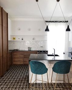 two blue chairs sitting in front of a kitchen island with black counter tops and white walls