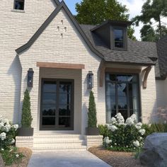 a white brick house with large windows and landscaping