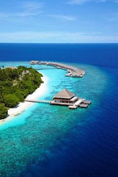 an island in the middle of the ocean with a dock and water villa on it