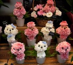 many pink and white flowers are in small vases on a wooden table next to plants