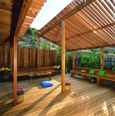 a wooden deck with benches under a pergolated roof