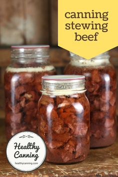 three jars filled with food sitting on top of a wooden table next to a sign that says canning stewing beef