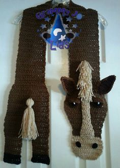 a knitted scarf hanging on the wall with a horse's head attached to it