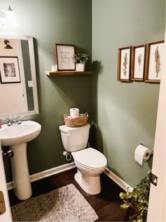 a bathroom with green walls and pictures on the wall above the toilet, along with a rug