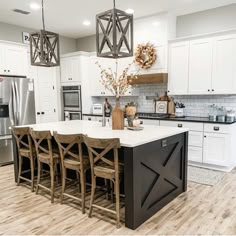 a kitchen with white cabinets and an island in front of the stove, refrigerator and sink