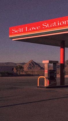 an empty gas station with a red sign that says self love station on it's side