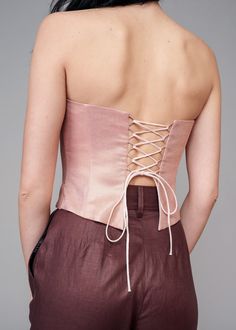 Elevate your style with the IRA LYSA Pink Metallic Corset. Stand out in the crowd while not compromising on comfort. The pink is delicate but the corset shape keeps this piece chic and high-fashion. * Made with corset boning* Air loops and long spaghetti strap on the back* Wave bottom finish Material: 100% European linen Handmade. Always. Luxury Bustier Corset With Bust Darts, Chic Sleeveless Corset With Lace-up Back, Chic Bandeau Corset With Corset Back, Chic Fitted Bandeau Corset, Chic Strapless Evening Corset Belt, Chic Strapless Corset Belt For Evening, Pink Strapless Corset With Boning, Evening Bandeau Fitted Corset, Fitted Bandeau Corset For Evening