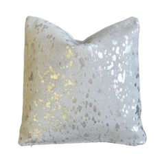 a silver and gold pillow on a white background, with small spots in the middle