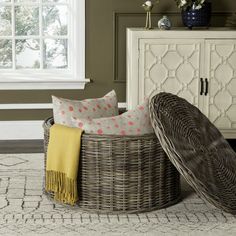 a wicker basket sitting on top of a rug next to a white cabinet and window