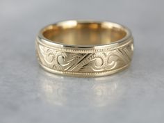 a wedding ring with an intricate design on the inside and outside, sitting on a gray surface