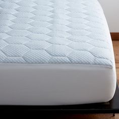 a close up view of a mattress on a bed frame with wood floors in the background