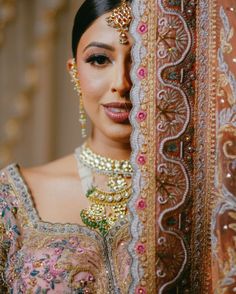 a woman in a bridal outfit looking out from behind a curtain with jewelry on her head