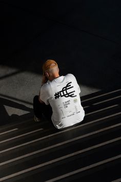 a person sitting on a bench talking on a cell phone and looking down at the ground