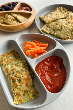 three plates with different types of food in them on a white table top next to some dipping sauces