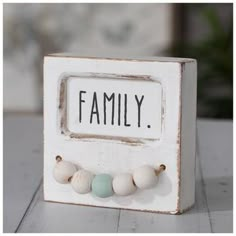 a family sign with beads hanging from it's sides on a white wooden block