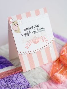 a pink and white gift card sitting on top of a quilt