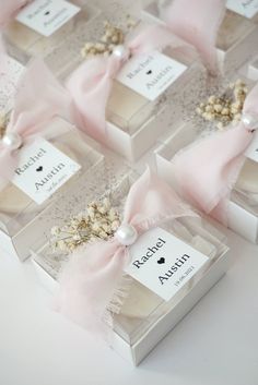 several small boxes with pink bows and pearls on them are sitting on a white surface