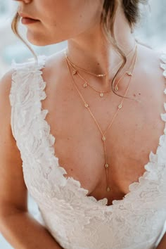 a woman wearing a white dress and gold necklace