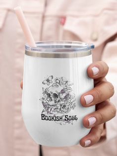 a woman holding a white cup with a straw in it's mouth and the words bookish soul on it