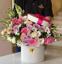 a white box with pink and purple flowers in it sitting on top of a table