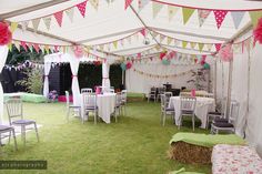 tables and chairs are set up in a tent for an outdoor party with bunting