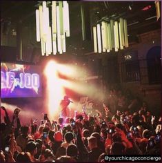 a large group of people at a concert in front of a stage with lights on it