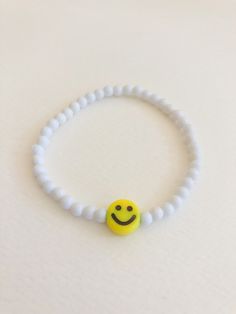 "customize your very own happy smiley face stretchy bracelet, made to order in your size! you will receive one white beaded bracelet with your choice of center smiley bead (gold or yellow). PLEASE NOTE: you will receive ONE bracelet with this order. these super trendy and versatile stretch bracelets are the perfect little accessory for your wrist. they are dainty and beautiful by themselves, but also look great when combined and stacked. you can add to your stack right here: http://www.etsy.com/ Handmade Accessories Bracelet, Bracelets With Smiley Faces, How To Make Trendy Bracelets, Fun White Bracelets For Everyday, Fun White Bracelet For Everyday Wear, Handmade Beaded Jewelry Bracelets, Fun White Everyday Bracelets, Fun White Bracelet For Everyday, Fun White Beaded Bracelets For Everyday