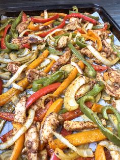 a tray filled with assorted bell peppers and sausages, ready to be cooked