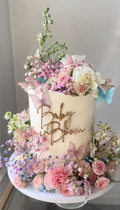 a white cake with pink and blue flowers on top that says baby b'tan