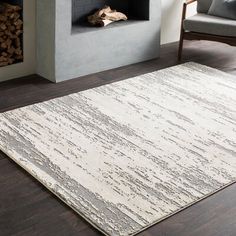 a living room area with a fireplace, chair and large rug on the hardwood floor