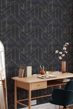 a desk and chair in front of a black wall with gold geometric design on it