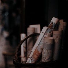 a basket filled with lots of books next to a vase full of candles on top of a table