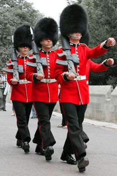 three men in red uniforms marching down the street