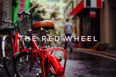 two red bikes parked next to each other on the side of a street with buildings in the background