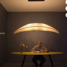 a man sitting at a table under a lamp