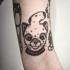 a cat tattoo on the left arm with scissors in it's mouth and eyes