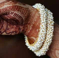 a woman's hand with henna and bracelets on her wrist, decorated with pearls