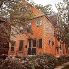 an orange house with lots of windows and bushes