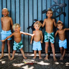 five children standing in front of a wooden wall with their arms around each other while one child holds his hand out