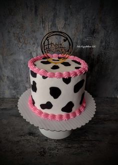 a birthday cake decorated with pink and black polka dots