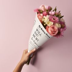 a person holding a bouquet of flowers on top of a pink background with the words i will you marry written on it