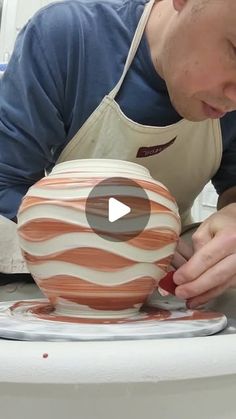 a man in an apron is working on a pottery bowl that has been painted orange and white