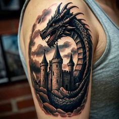 a woman's arm with a dragon and castle tattoo on the side of her shoulder