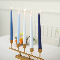 five candles are lit on a table with flowers in the background