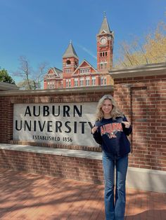 a woman standing in front of the auburn university sign