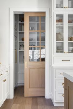 an open door leading to a kitchen with white cupboards and drawers on either side